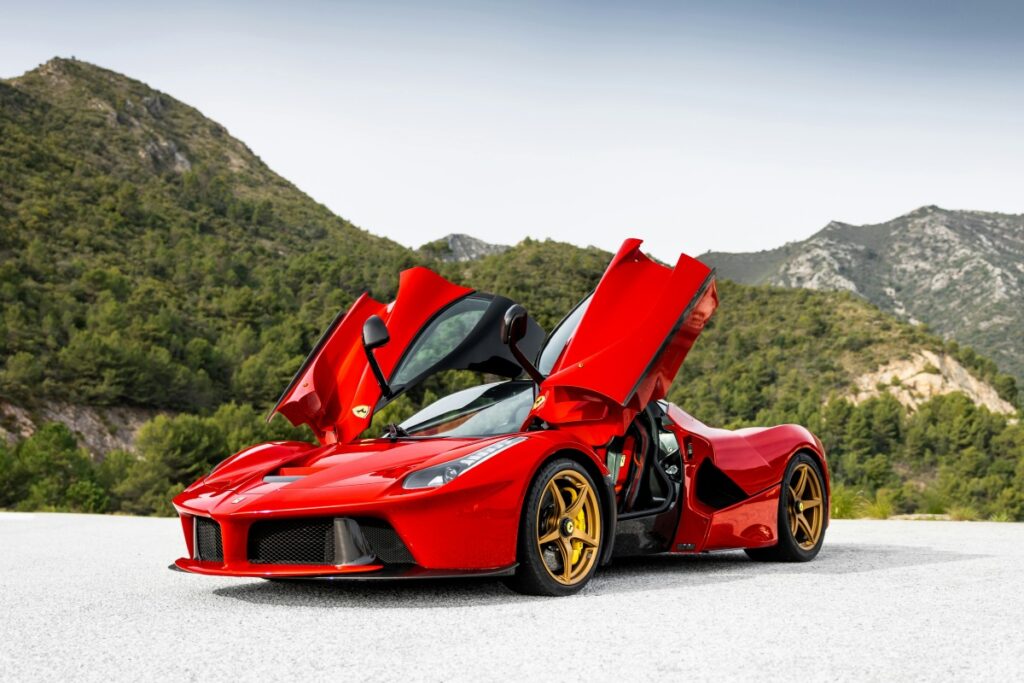 Auf dem Bild steht ein imposanter, roter Supercar mit aufgerissenen Türen vor einer landschaftlichen Kulisse aus Bergen und Wäldern. Wie dieser Sportwagen die neuesten Technologien und Design-Trends vereint, so reflektieren "Die Social-Media-Marketing-Trends 2025 in Österreich" die neuesten Entwicklungen und Strategien auf dem österreichischen Social-Media-Markt.